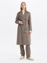 A lady wears a plaid trench coat.